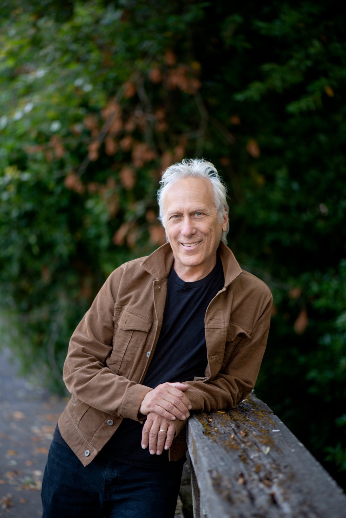Larry Bragman leaning on a wooden fence outdoors
