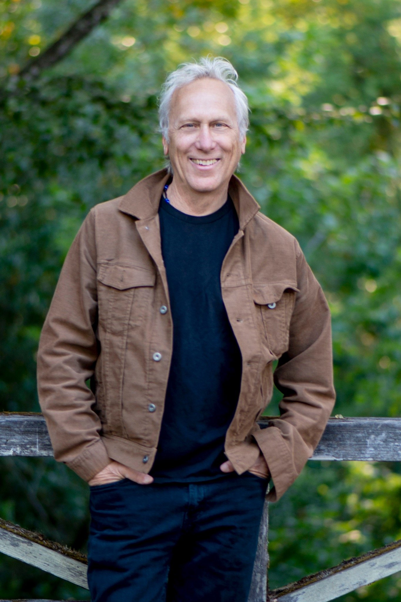 Larry Bragman standing beside a wooden fence outdoors